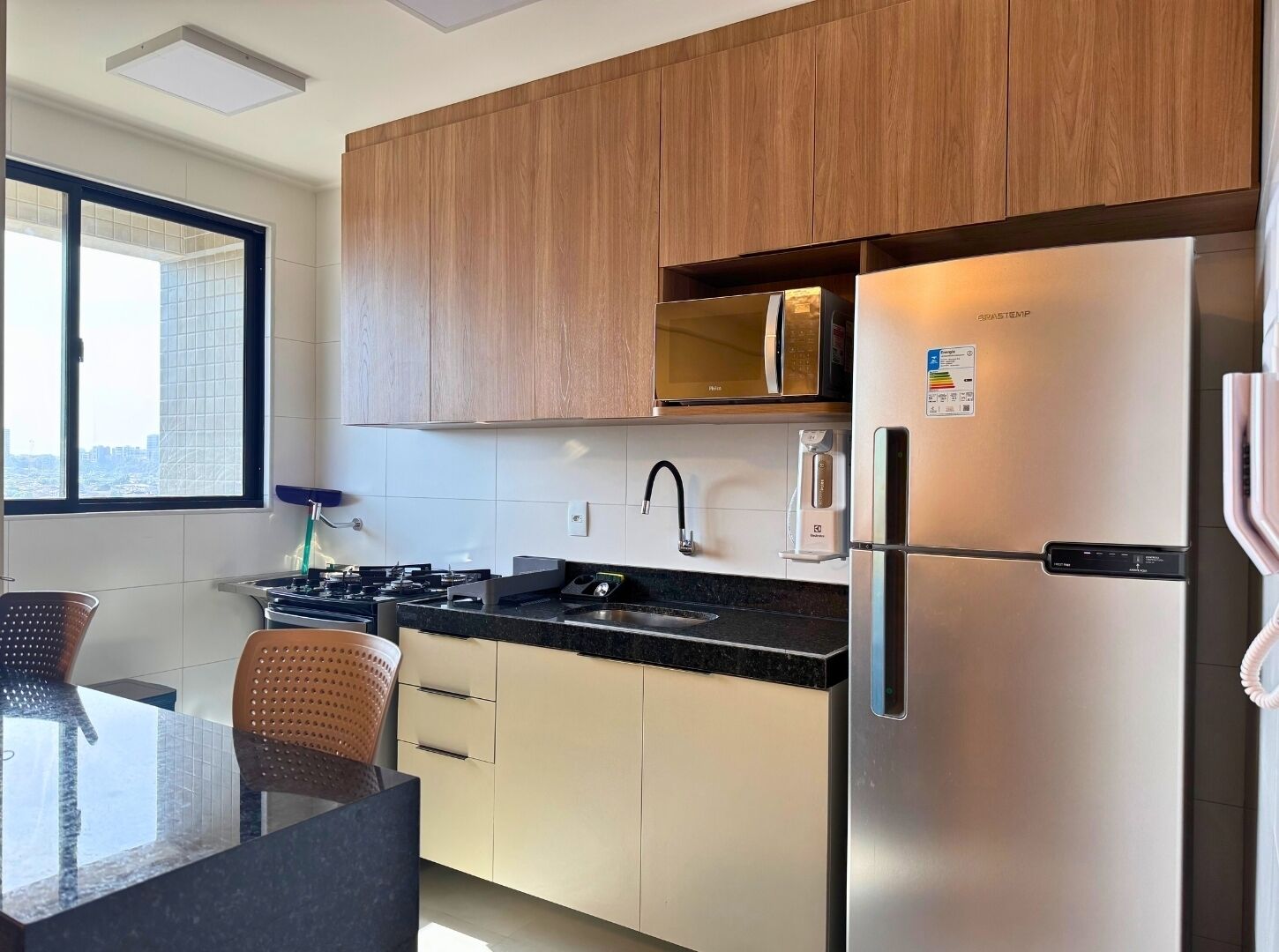A modern kitchen with wooden cabinets, a stainless steel refrigerator, a microwave, and a gas stove.
