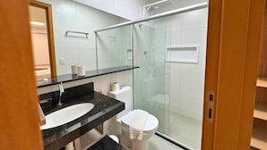 A modern bathroom with a glass shower enclosure, a white toilet, and a black granite sink. - Studio Design 3 Apt 902 (Maceio)