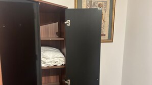 Ένα δωμάτιο με μια ντουλάπα, ένα κρεβάτι και έναν πίνακα κρεμασμένο στον τοίχο.