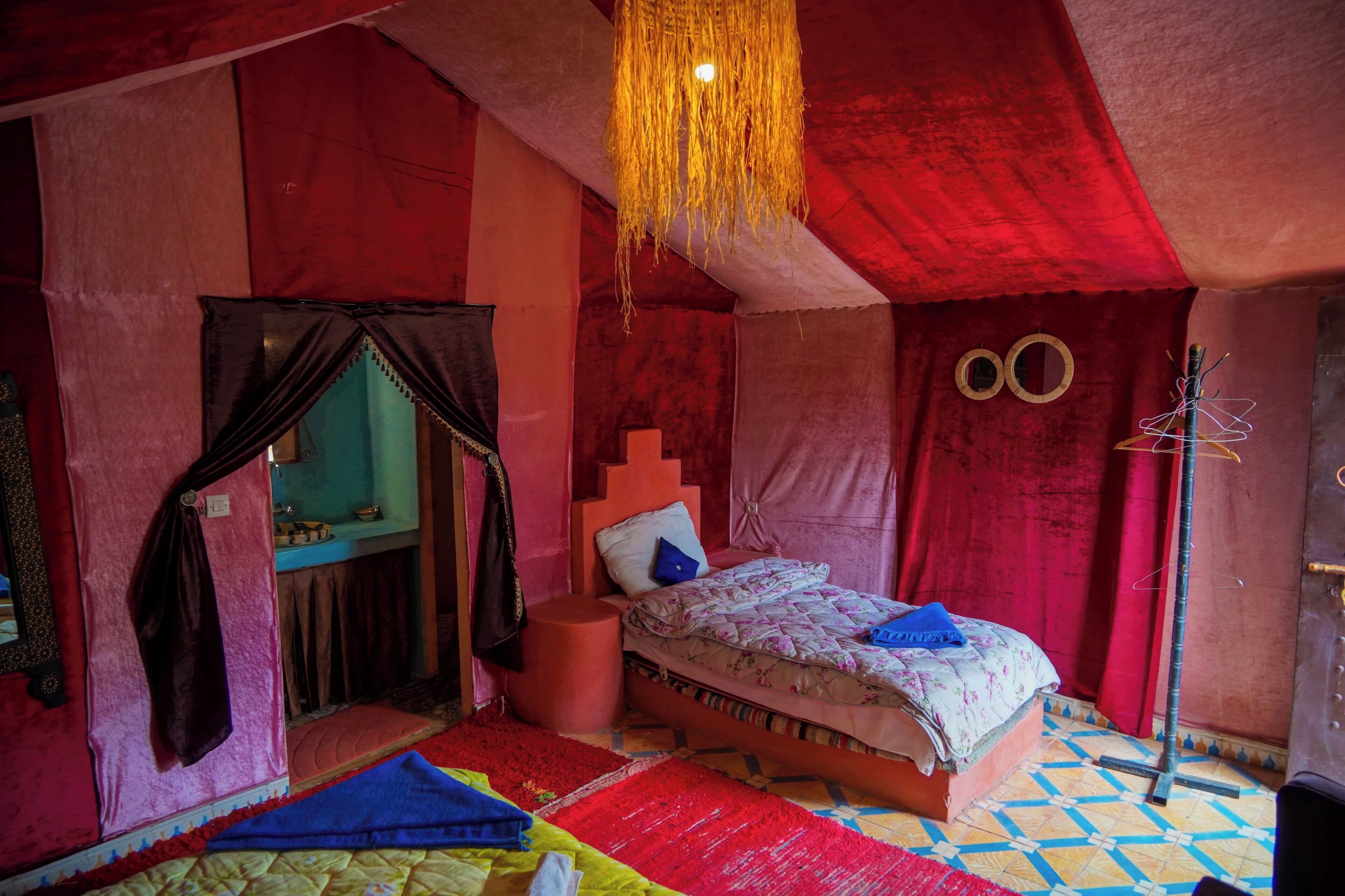 A room with a bed, a hanging light fixture, a mirror, and a wall with circular decorations.