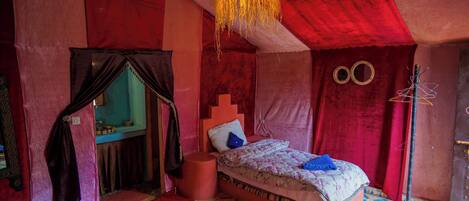 A room with a bed, a hanging light fixture, a mirror, and a wall with circular decorations.