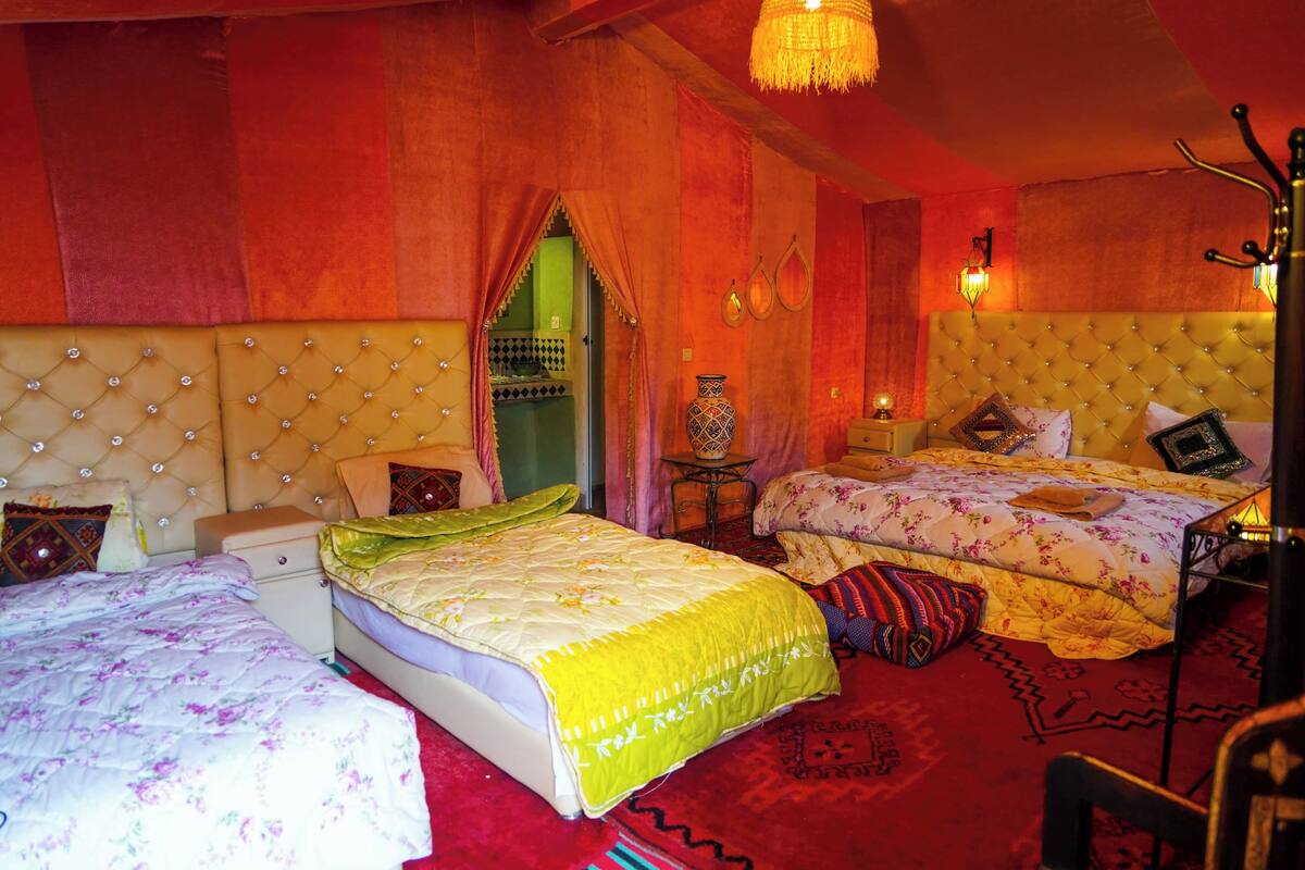 Ein Zimmer mit zwei Betten, einem Chandelier und einem kleinen Tisch mit einer Vase.