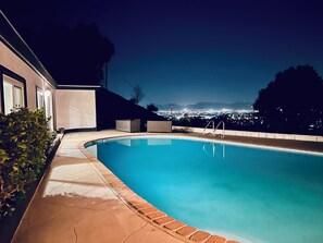 Una piscina con vista sulla città illuminata di notte.