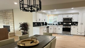 A modern kitchen with white cabinets, a built-in microwave, and a large stove. - Private Hillside Pool Home with View close to Yaamava and Glen Helen  (San Bernardino)