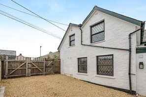 A two-story building with a white exterior, a wooden fence, and a gravel driveway.