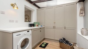 A compact laundry room with a washing machine, cabinets, a clock, and a small window. - 3 Bed in West Down (oc-r29627) (West Down)
