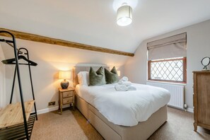 A bedroom with a bed, bedside table, lamp, and a window with a view.