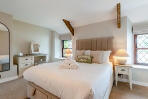 A bedroom with a large bed, bedside tables, a dresser, and a window with a view.