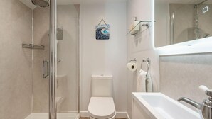 A modern bathroom with a glass-enclosed shower, a toilet, and a bathtub. - 3 Bed in West Down (oc-r29627) (West Down)