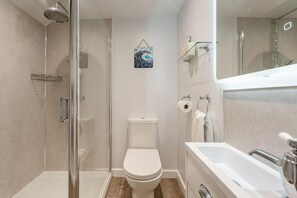 A modern bathroom with a glass-enclosed shower, a toilet, and a bathtub.