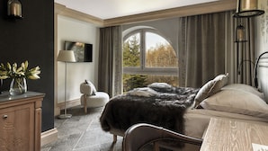 A bedroom with a large window, a bed with a dark blanket, a bedside table, and a lamp. - Willa na Kozińcu (Zakopane)
