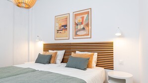 A modern bedroom with a wooden slatted headboard, a green bedspread, and two framed abstract paintings on the wall. - Ida - Rental in Rincon de la Victoria (Rincón de la Victoria)