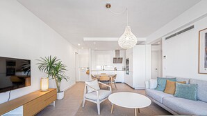 A modern living room with a sofa, a coffee table, a TV, and a dining area with chairs and a table. - Ida - Rental in Rincon de la Victoria (Rincón de la Victoria)