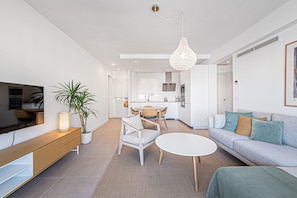 Una sala de estar moderna con un sofá, una mesa de centro, un televisor y un comedor con sillas y una mesa.