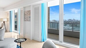 A modern living room with a large sliding glass door leading to a balcony with a city view. - Ritz-Carlton Luxury - Oceanfront 2BR on 16th Fl (Fort Lauderdale)
