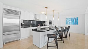 A modern kitchen with a central island, stainless steel appliances, and bar stools. - Ritz-Carlton Luxury - Oceanfront 2BR on 16th Fl (Fort Lauderdale)