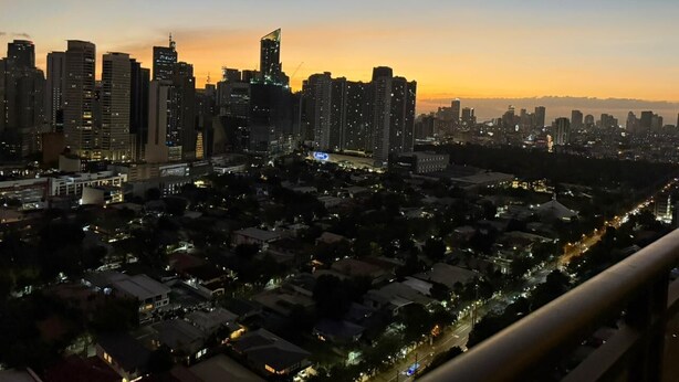 A cityscape at dusk with high-rise buildings and a mix of residential and commercial structures. - One Bedroom with Balcony City view  (Makati)