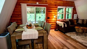 Interior acogedor de una cabaña con comedor, sofá y ventilador de techo.