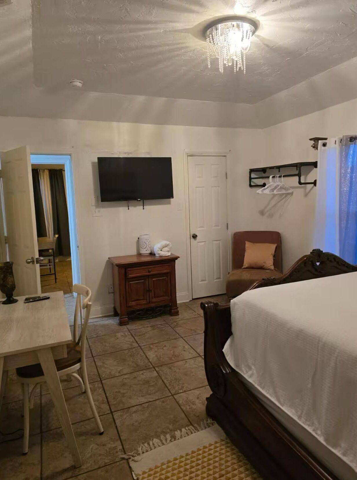 A bedroom with a bed, a TV, a desk, and a chair.