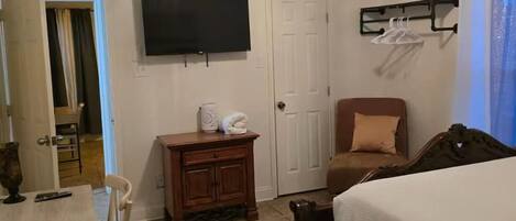 A bedroom with a bed, a TV, a desk, and a chair.
