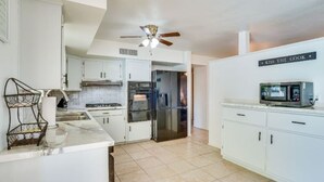 A modern kitchen with white cabinets, a microwave, and a ceiling fan. - Charming 3-bedroom house with WiFi, AC in delightful Tucson (Tucson)
