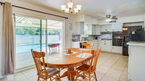 A modern kitchen with white cabinets, a central island, and a dining area with a wooden table and chairs. - Charming 3-bedroom house with WiFi, AC in delightful Tucson (Tucson)