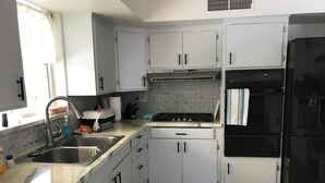 A kitchen with white cabinets, a black refrigerator, a gas stove, and a sink. - Charming 3-bedroom house with WiFi, AC in delightful Tucson (Tucson)