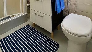 Un bagno con doccia, lavandino, specchio e toilette.