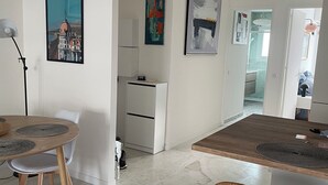 A modern kitchen with white cabinetry, a dining area with a round table and chairs, and a bar area with a wooden counter. - Bright, quiet apartment between the beach and Antibes old town, with parking (Antibes)