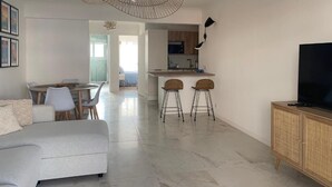 A modern living room with a grey sofa, a dining area with a round table, and a kitchen with a bar area. - Bright, quiet apartment between the beach and Antibes old town, with parking (Antibes)