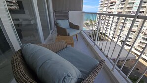 A balcony with wicker furniture, a glass door, and a view of a residential area.