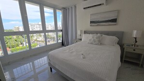 A hotel room with a large bed, a nightstand, a lamp, and a painting on the wall.