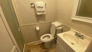 A small, compact bathroom with a toilet, sink, and a towel rack.