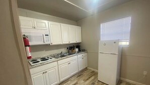 A compact kitchen with white cabinets, a microwave, a stove, and a refrigerator. - The Preserve of Texas / C7 (Cleveland)