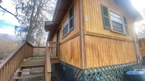 A wooden cabin with a wooden staircase leading to a deck, surrounded by trees. - The Preserve of Texas / C7 (Cleveland)