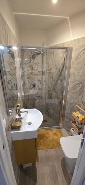 Une salle de bain moderne avec une douche à parois de verre, un lavabo blanc et un meuble-lavabo en bois.
