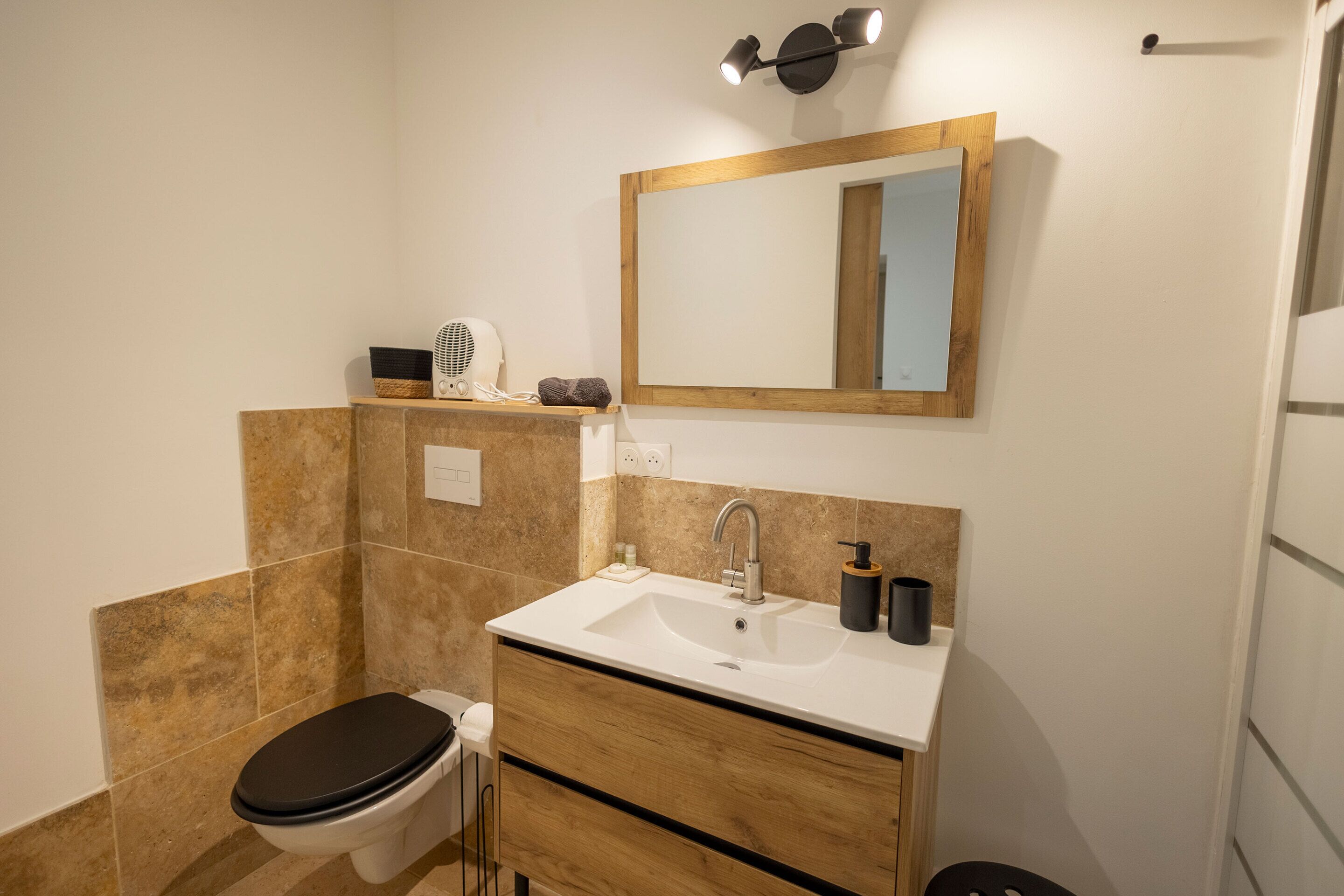 Une salle de bain avec un lavabo blanc, un meuble-lavabo en bois et un miroir au-dessus du lavabo.