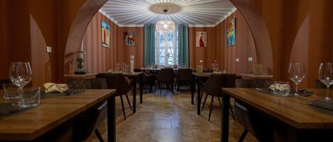 Un comedor con techo alto abovedado, una araña y obras de arte en las paredes.