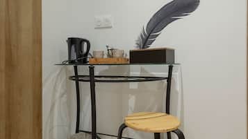 A small, modern room with a glass table, a wooden chair, and a decorative feather on the table.
