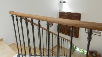 Una escalera de madera con barandilla de metal, un armario de madera y una planta pequeña en el suelo.