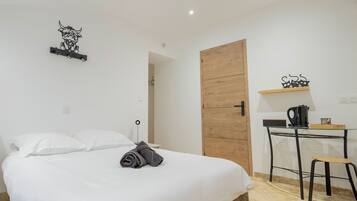 Une chambre d’hôtel avec un lit, un bureau, une chaise, une machine à café et une porte en bois.