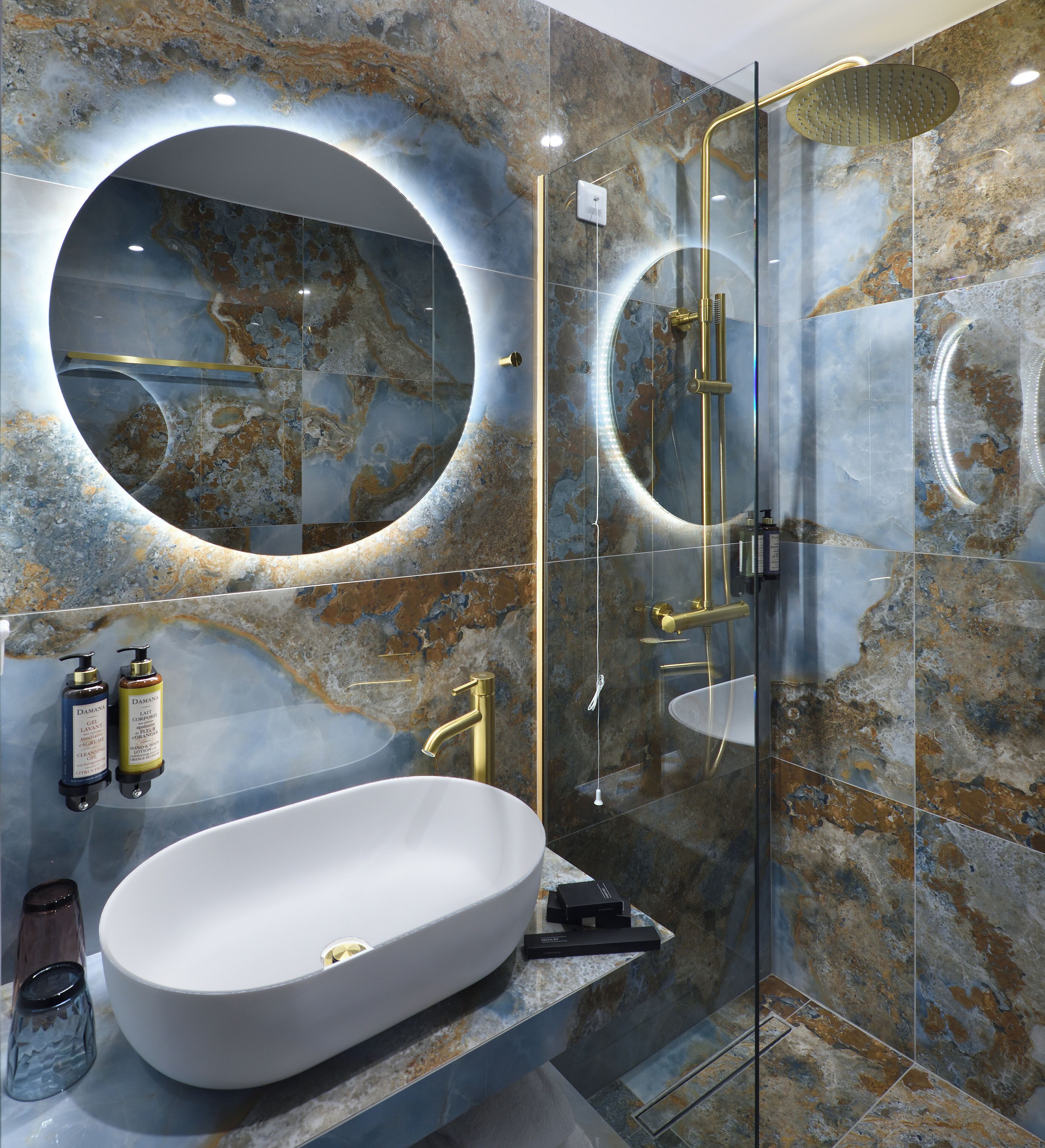 A modern bathroom with a large oval sink, a glass-enclosed shower, and a circular mirror above the sink.