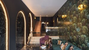 A modern lobby with a marble floor, a green sofa with leopard print cushions, and a staircase leading to upper floors. - The Oscar Olympic Hotel (Thessaloniki)