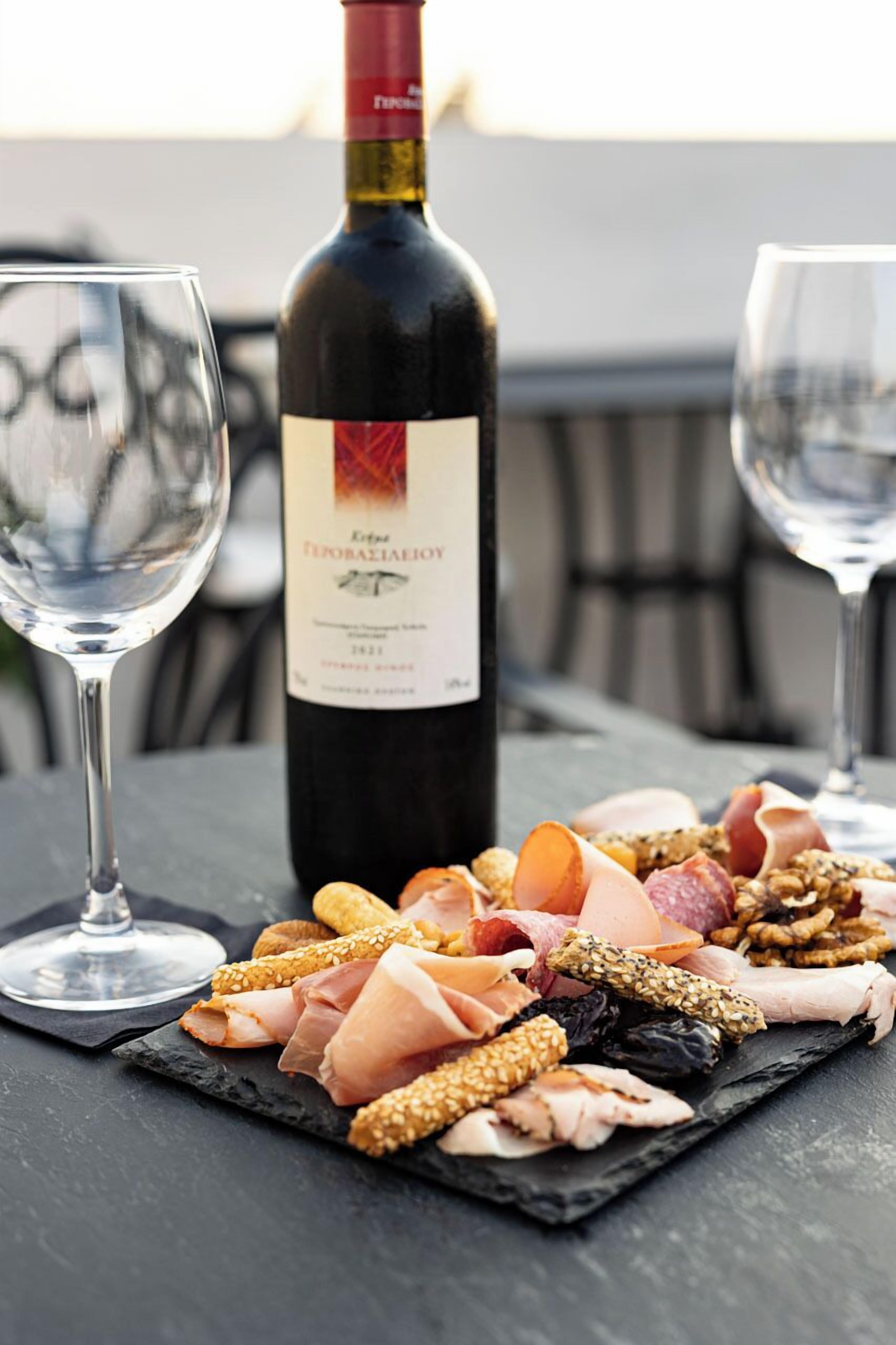 Une bouteille de vin portant l’étiquette « Extra Finoresiaioy » est posée sur une table, entourée d’une variété de viandes et de fromages, et deux verres à vin l’accompagnent.