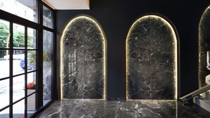 A modern interior with two arched wall panels featuring a marble finish and integrated lighting. - The Oscar Olympic Hotel (Thessaloniki)