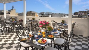 A rooftop café with checkered flooring, outdoor seating, and a view of the cityscape. - The Oscar Olympic Hotel (Thessaloniki)