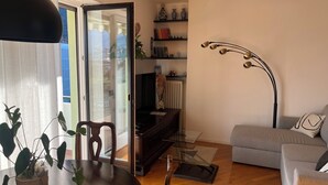 Un salon comprenant une table à manger, des chaises, un canapé, une lampe sur pied et une bibliothèque.