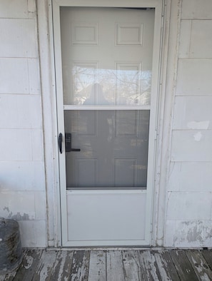 A white door with a screen door and a keypad lock.