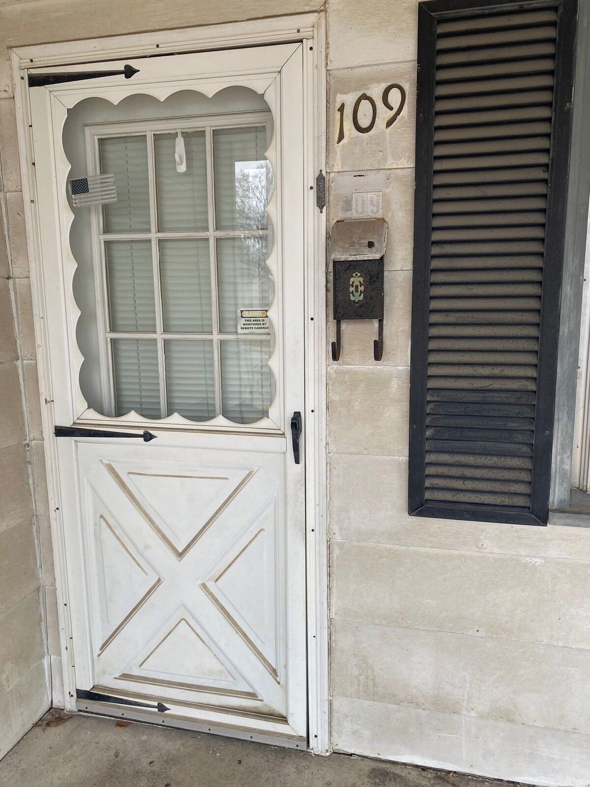 A white door with a glass panel and a black mailbox with the number 109 on the wall beside it.