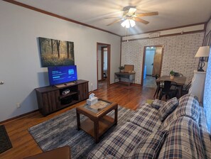 A living room with a television, sofa, coffee table, and a ceiling fan.
